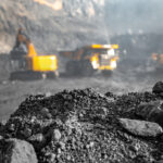 a pile of dirt with construction vehicles in the background